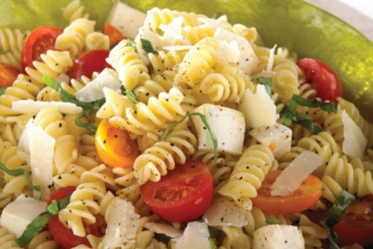 Closeup of pasta salad with salsa cruda in a green bowl